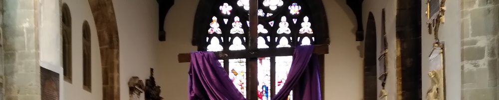 A small children's altar in front of the nave altar both dfressed in purple with a large wooden cross behind