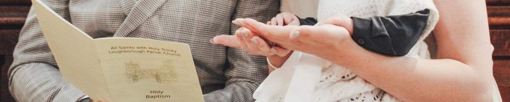 A couple holding a service sheet and a small chid lin a christening gown