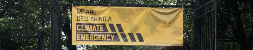 All Saints church community stood in a crowd under a yellow banner declaring a climate emergency