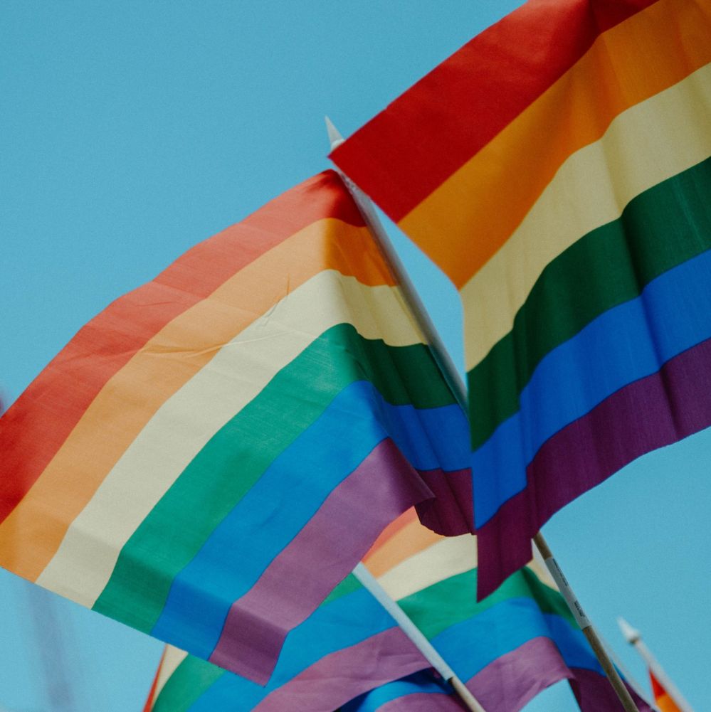 Classic pride rainbow flags flying in the breeze against a blue sky