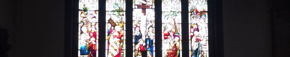 A plain wooden cross with a lit candle