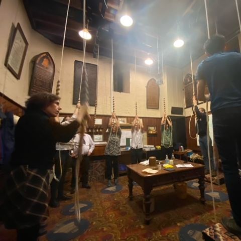 A group of people holding ropes for bells