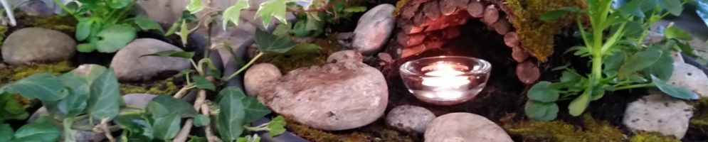 A small Easter Garden at the base of the font with a lit candle in the empty tomb