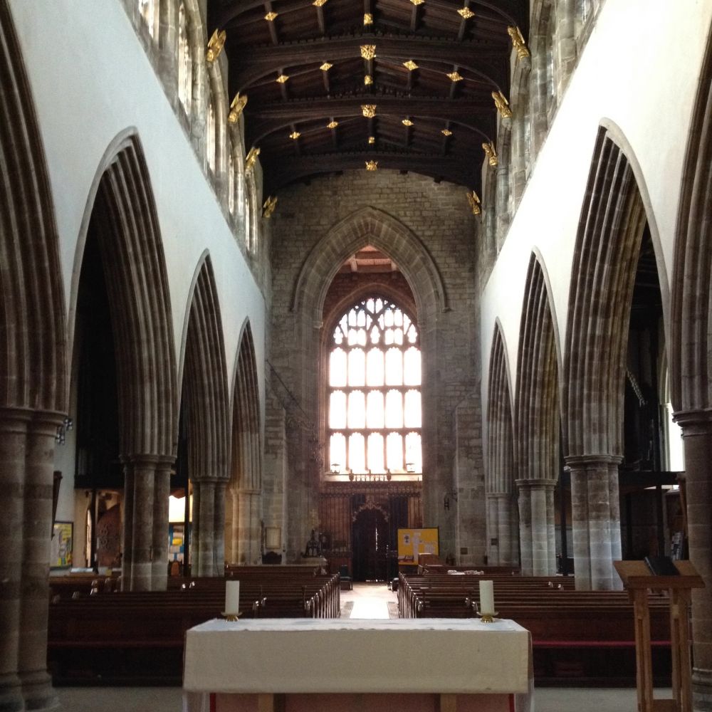 A view of the church from behind the latar looking towards the west end with the stain glass window and high nave ceiling in view