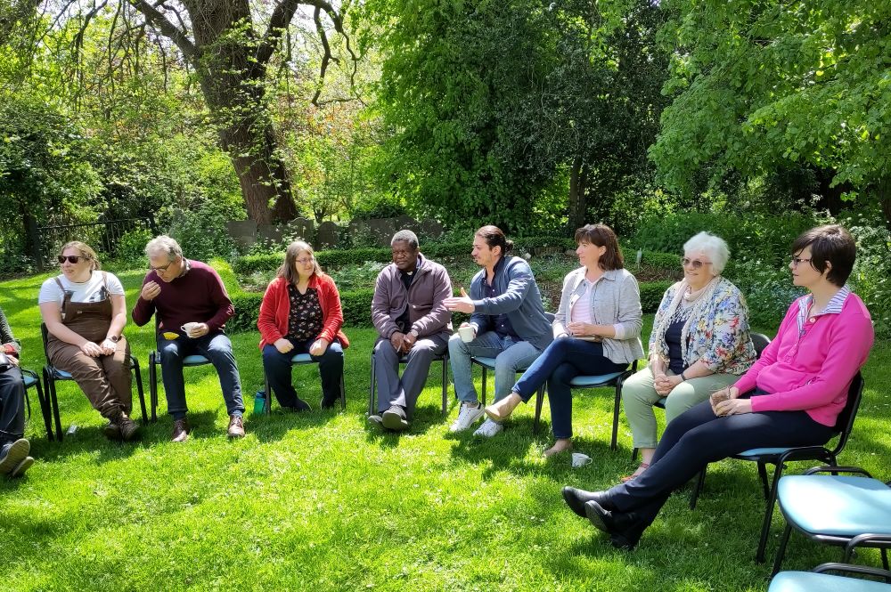 A group of people sitting on chairs on the grass