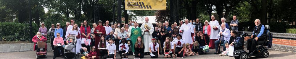 A crowd of people stood under a banner declaring a climate emergency