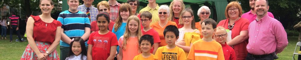 A children's choir stood in a field with brightly coloured t shirts
