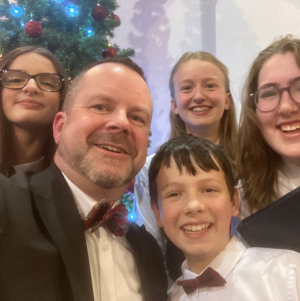Choral conductor pictured with four young people at a concert