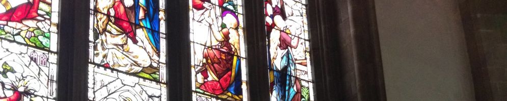 A side view of the altar with two candles and a cross in the middle with stained glass window